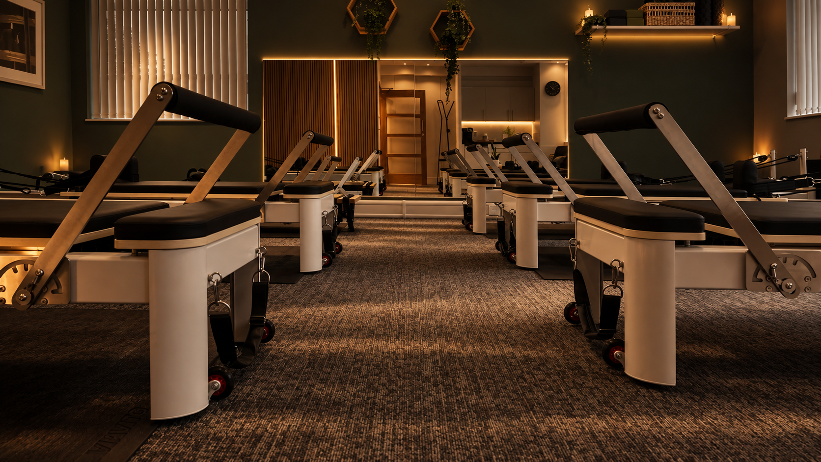 Five reformer machines arranged in a light-filled boutique pilates studio